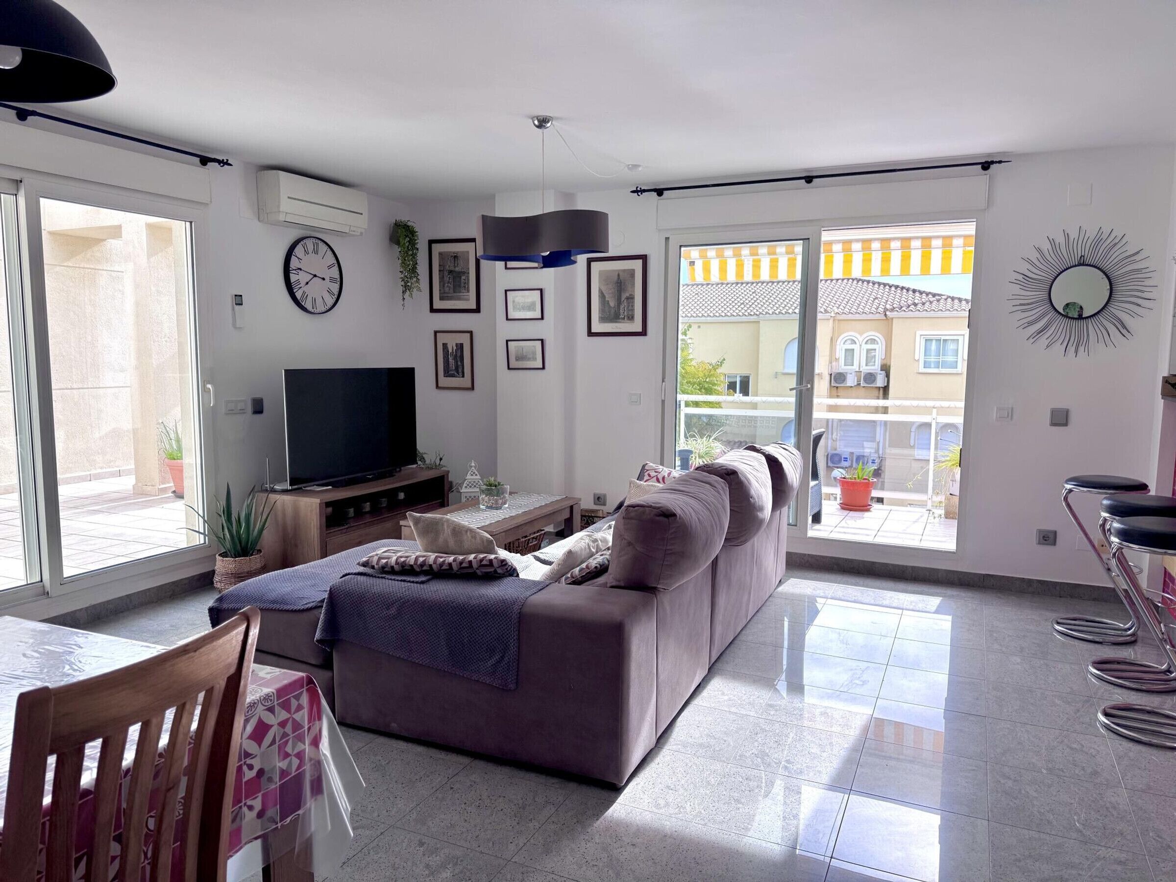 Una sala moderna con sofá, televisor y comedor.