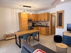 Una cocina moderna con armarios de madera, una mesa de comedor con sillas, un sofá, un televisor y una pequeña mesita auxiliar.