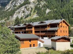 Una cabaña de madera de varios pisos con balcones, con montañas al fondo.