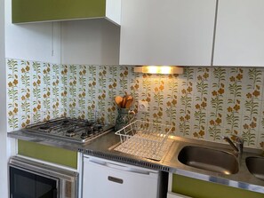 A compact kitchen with a gas stove, a sink, and a refrigerator. - Cozy T3 Apartment with Terrace in Canet-en-Roussillon (Canet-en-Roussillon)
