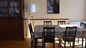 Un coin repas avec une table dressée pour quatre personnes, entourée de chaises, un meuble avec des portes en verre et une lampe fixée au mur.