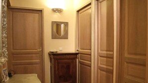 Un couloir avec des portes en bois, un miroir et un petit meuble en bois.