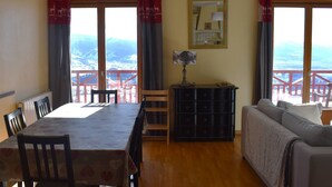 Une pièce comprenant une table à manger, des chaises, un canapé, un petit meuble et un miroir au mur.