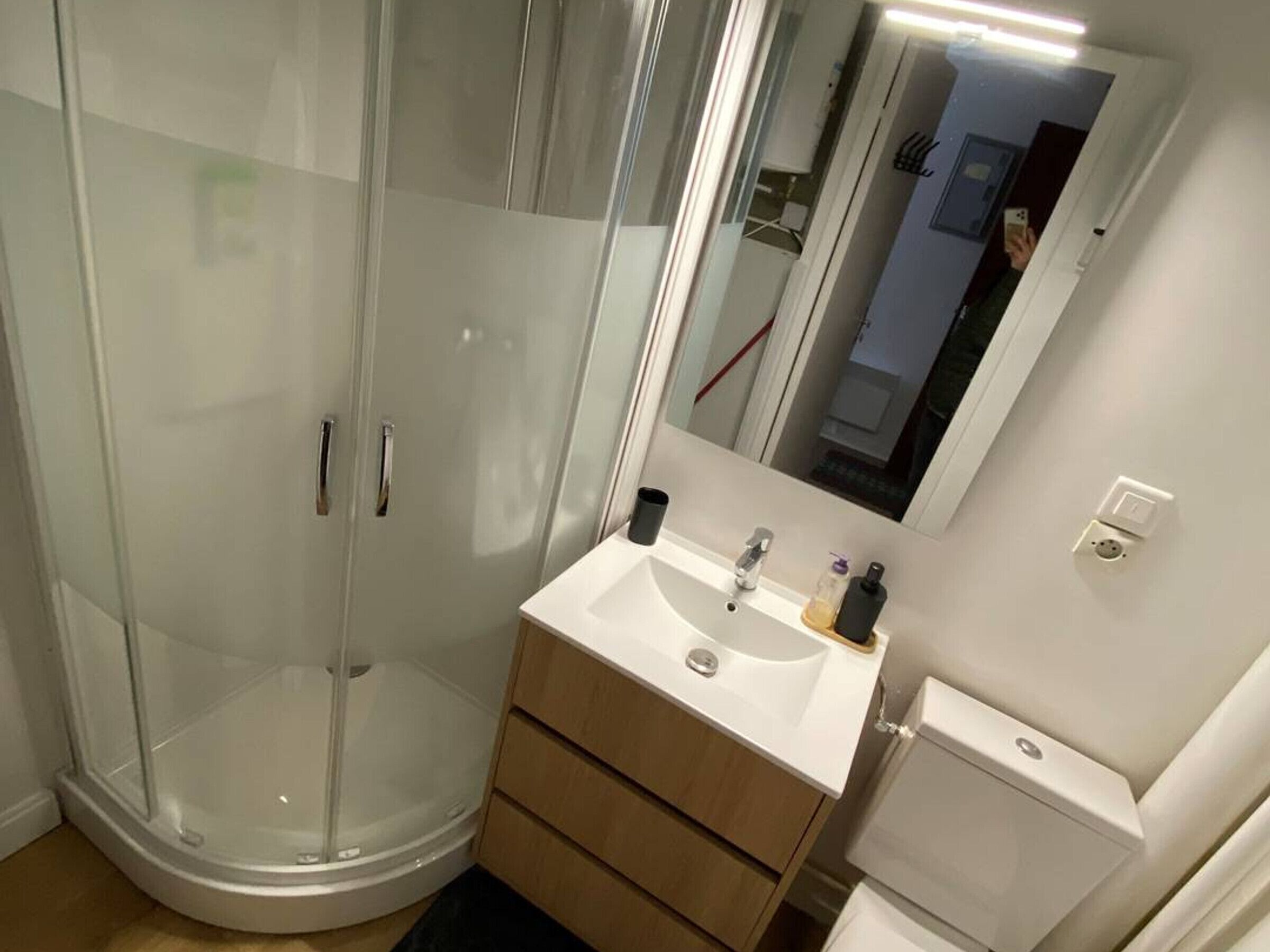 A bathroom with a glass-enclosed shower, a sink with a mirror, and a toilet.