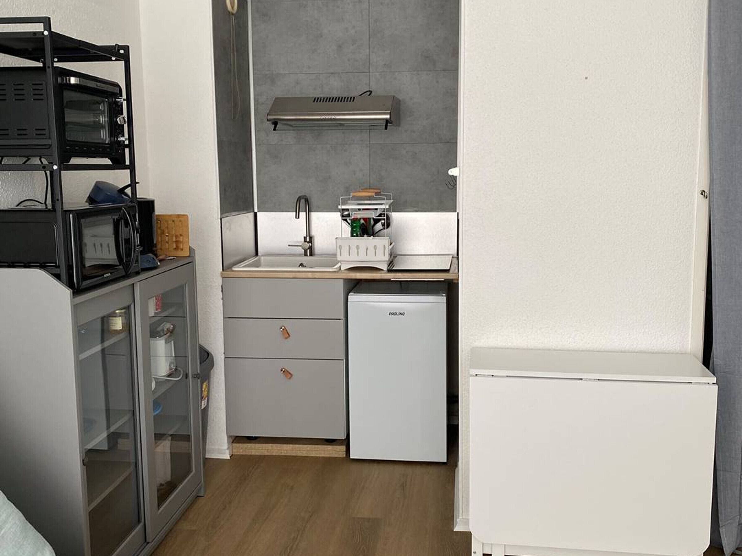 Een kleine keuken met een magnetron, spoelbak en koelkast.