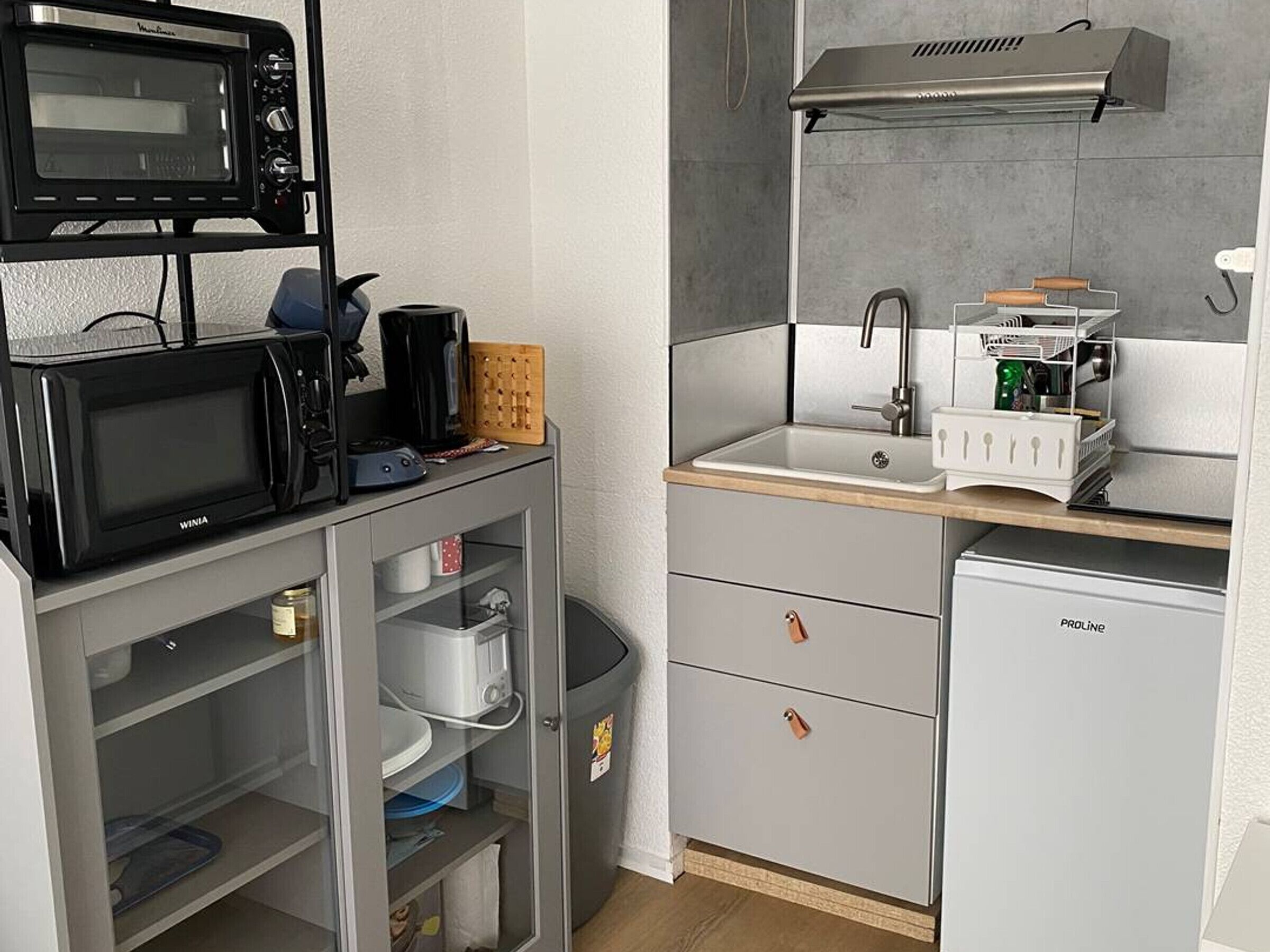 Pieni, käytännöllinen keittiönurkkaus, jossa on mikroaaltouuni, kahvinkeitin ja pieni jääkaappi.