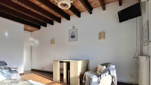 A spacious room with a wooden ceiling, a bed with a white and gray blanket, a blue sofa, a small wooden table, and a chair with a gray blanket. - Cozy T2 Cabin with enclosed loggia (Bolquère-Pyrénées 2000)