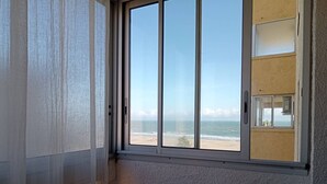 Ein Zimmer mit einem großen Fenster mit Blick auf einen Strand.