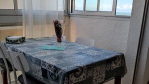 Ein Esstisch mit kariertem Tischtuch, Stühlen und einer Blumenvase.