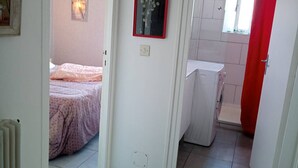Ein Schlafzimmer mit einem Bett, einem Nachttisch und einem Fenster mit rotem Vorhang.