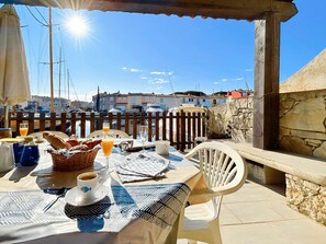 A table set outdoors with breakfast items, a view of boats and buildings, and a stone wall. - Large fisherman's house near beach - 4 terraces, WiFi, parking (Port Grimaud)