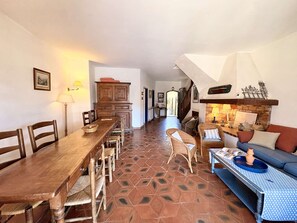 A spacious living area with a wooden dining table, wicker chairs, a blue sofa, and a fireplace. - Large fisherman's house near beach - 4 terraces, WiFi, parking (Port Grimaud)
