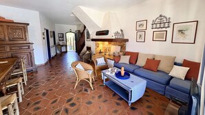 Ein großzügiger Wohnbereich mit Sofa, Sesseln, Couchtisch und Kamin.