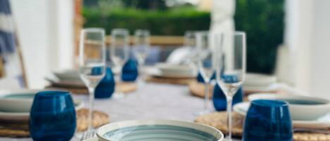 A table set with plates, glasses, and cutlery, arranged on woven placemats.