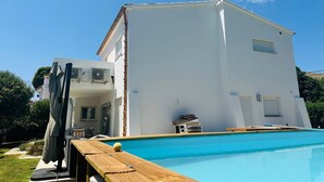 A white two-story building with a swimming pool in front. - Modern villa with private garden and pool. Ideal for families or small groups. (Las Palmeras)