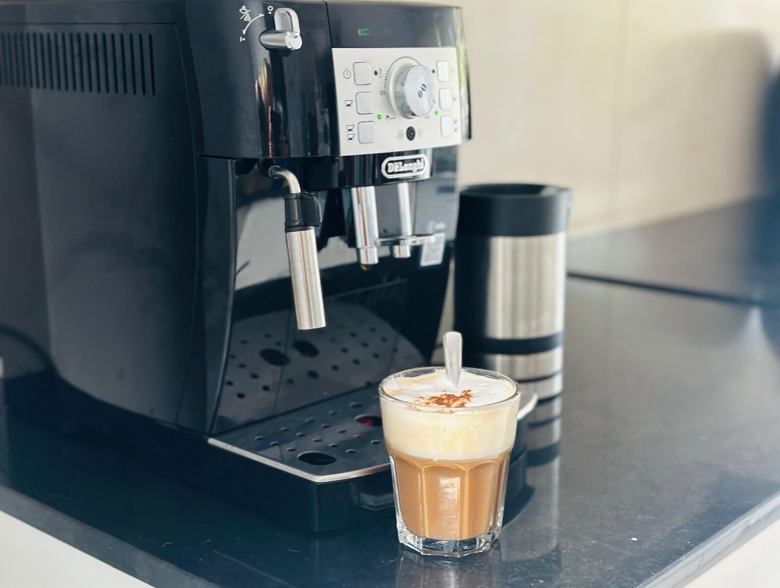 A coffee machine with a glass of iced coffee on a countertop.