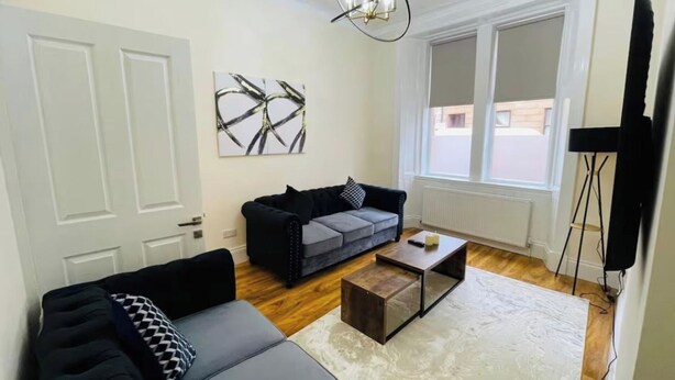 A modern living room with a grey sofa, a black sofa, a coffee table, and abstract art on the wall. - Near Hampden - Parking - Wifi - Sleeps 6 (Glasgow)