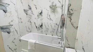 A bathroom with a glass-enclosed shower, white marble tiles, and a white bathtub. - Near Hampden - Parking - Wifi - Sleeps 6 (Glasgow)
