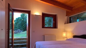 A bedroom with a bed, a window, a radiator, and a door leading to an outdoor area. - Stunning Panoramic Villa (Punta Ala)