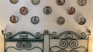 A wall with multiple decorative plates and a metal bed frame. - Stunning Panoramic Villa (Punta Ala)