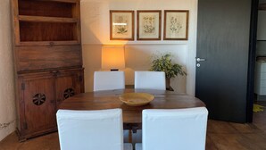 A dining area with a wooden table, white chairs, a lamp, and framed botanical prints on the wall. - Stunning Panoramic Villa (Punta Ala)