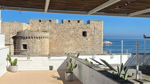 A rooftop terrace with a view of a historic stone wall and the sea. - Seafront Apartments by Carlo V Castle, Monopoli Old Town - HelloAPULIA Al Castello di Amec (Monopoli)
