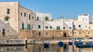 A coastal town with white buildings, a calm harbor, and boats. - Seafront Apartments by Carlo V Castle, Monopoli Old Town - HelloAPULIA Al Castello di Amec (Monopoli)