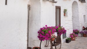 A traditional building with a conical roof and a bicycle with flowers. - Seafront Apartments by Carlo V Castle, Monopoli Old Town - HelloAPULIA Al Castello di Amec (Monopoli)