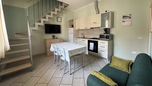 A compact living space with a kitchen, dining area, and a staircase. - Neptune Apartment Relax Privè Beach (Cervia)