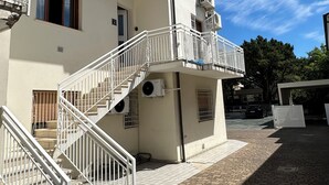 A two-story building with a balcony, a staircase, and an air conditioning unit. - Neptune Apartment Relax Privè Beach (Cervia)