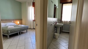 A hotel room with a bed, a bathroom with a sink and mirror, and a view of the adjacent room. - Neptune Apartment Relax Privè Beach (Cervia)