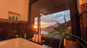 A bathroom with a bathtub, candles, and toiletries on the counter.
