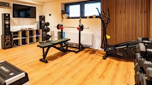 A home gym with a bench press, squat rack, and dumbbells. - Villa Tauris - Lake Lucerne - Private Spa & Natural Pool (Emmetten)