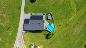 An aerial view of a property with a large building, a swimming pool, and a fenced area. - Villa Tauris - Lake Lucerne - Private Spa & Natural Pool (Emmetten)