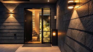A modern entrance with a glass door leading to a staircase and a wall-mounted light fixture.