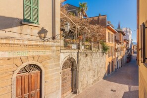 A narrow street with historic buildings, a stone wall, and a wooden gate. - Dream Lake Home by Varenna Holidays (Varenna)