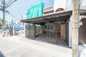 A building with a covered entrance, metal gates, and a concrete pillar. - FunnD Mrt lat phrao 5Beds NetflixYouTube (Bangkok)