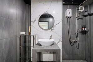 A modern bathroom with a marble wall, a round mirror, a white sink, a glass shelf, and a shower area. - FunnD Mrt lat phrao 5Beds NetflixYouTube (Bangkok)