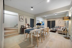 Un salon moderne avec un coin repas, comprenant un escalier, un téléviseur à écran plat et un canapé.