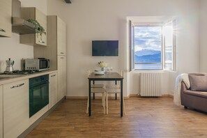 A modern kitchen with a dining table, a TV, and a view of the sea. - Stunning View by Varenna Holidays (Varenna)
