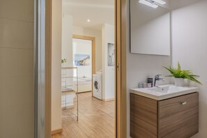 Een moderne badkamer met een houten wastafelmeubel, een witte wasbak en een spiegel.