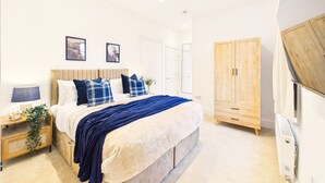 A bedroom with a bed, bedside tables, a wardrobe, and a mirror. - *NEW* Artisan Court | Central | Modern | Parking (Gloucestershire)