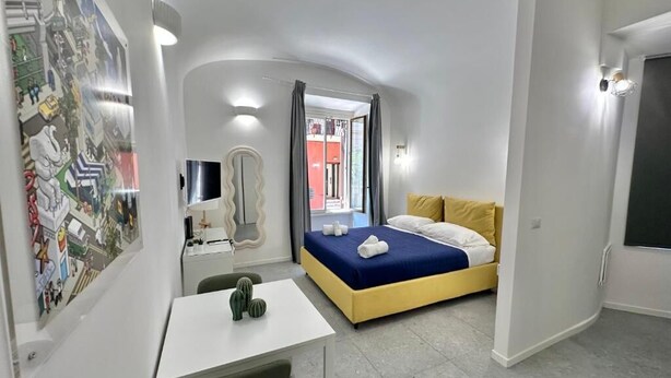 Un dormitorio moderno con una cama, un escritorio y una silla. Hay una ventana con cortinas, una puerta y una pared con un mural.