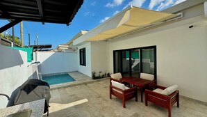 Une terrasse avec une piscine, du mobilier d’extérieur et un barbecue.