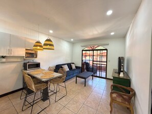 A compact living space with a kitchenette, dining area, sofa, and a TV. - Plaza Colonial Second Floor One Bedroom Unit (Playas Del Coco)