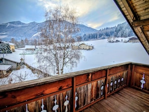 A wooden balcony with a view of a snow-covered landscape, including houses and mountains. - Apartment 'Grabmairhof Ahrntal' with Mountain View (Lutago)