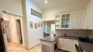 Una cocina con armarios blancos, piso de baldosas y una pequeña isla.