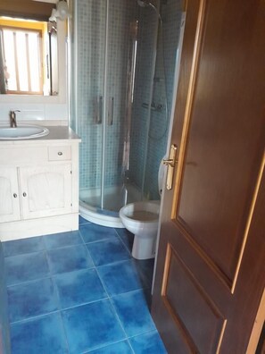 Un bagno con un mobile lavabo bianco, uno spazio doccia e un water.