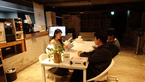 A room with a coffee machine, a computer, a table with a plant, and a cake. - ORAGO stay hotel (Suwon)