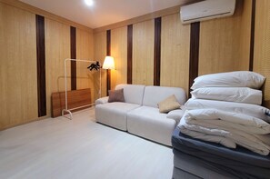 Ein Hotelzimmer mit einer Couch, einer Lampe, einem Bett mit Kissen und einer Wandklimaanlage.